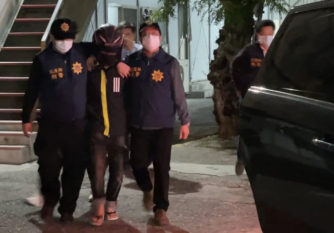 Nghi can người Việt (giữa) được cảnh sát quận Hoa Liên hộ tống về nơi điều tra. Ảnh: TWN 