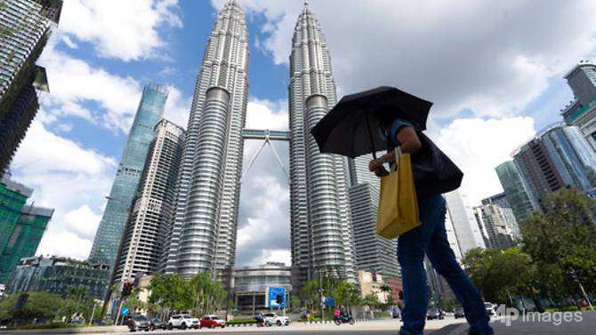 Một người phụ nữ Malaysia đeo khẩu trang đi bộ trước Tòa tháp đôi ở Kuala Lumpur, hôm 7/5/2021. Ảnh: AP 