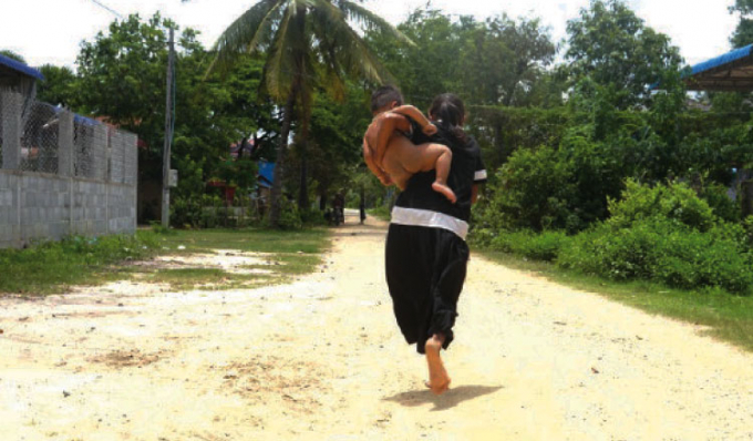 A woman carries her naked child in an impoverished Cambodian village. Photo: KT 