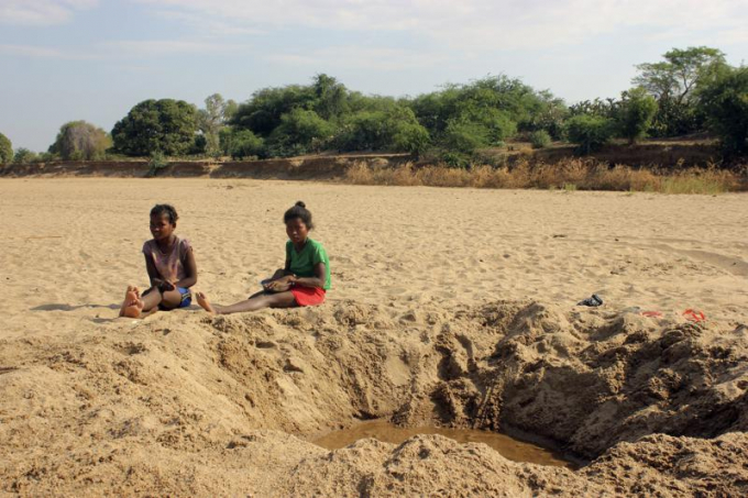 FILE - In this Nov. 11, 2020, file photo, children sit by a dug out water hole in a dry river bed in the remote village of Fenoaivo, Madagascar. Lola Castro, WFP’s regional director in southern Africa, told a news conference Friday, June 25, 2021, that she witnessed 'a very dramatic and desperate situation' during her recent visit with WFP chief David Beasley to the Indian Ocean island nation of 26 million people. (AP Photo/Laetitia Bezain, File)