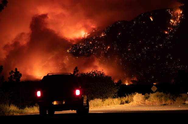 A motorist watches as a wildfire burns on the side of a mountain in Lytton, Canada on July 1, 2021. AP