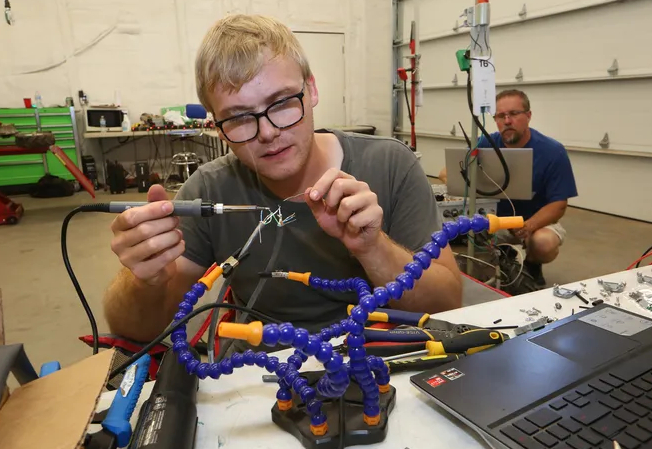 Nicholas Moehring, an electrical engineering intern from Wichita State University works on a robot. Photo: The Hutchinson News  