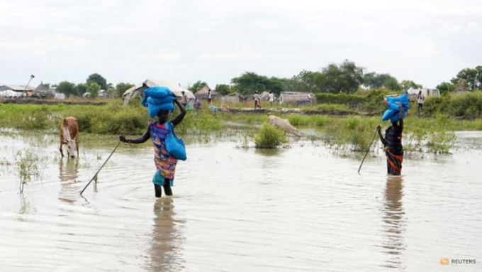 Women carry sacks on their heads as they walk through water, after heavy rains and floods forced hundreds of thousands of people to leave their homes, in the town of Pibor, Boma state, South Sudan, on Nov 6, 2019. Photo: REUTERS/Andreea Campeanu