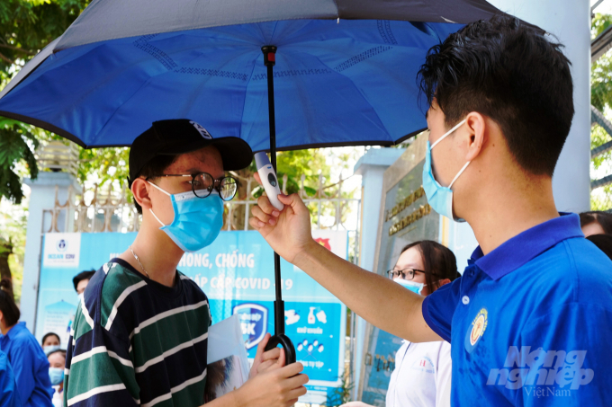 Thí sinh và người nhà thí sinh được đo thân nhiệt, yêu cầu đeo khẩu trang, sát khuẩn trước khi vào điểm thi. Ảnh: VD.