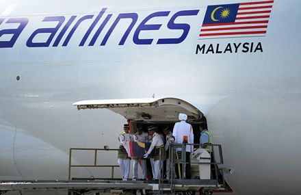 Các binh sĩ khiêng quan tài của nạn nhân ra khỏi máy bay tại sân bay Kualar Lumpur sáng 22/8.