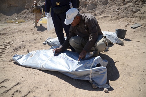 A member from the Iraqi forensic team writes on the body bag of remains belonging to Shi'ite soldiers from Camp Speicher who have been killed by Islamic State militants at a mass grave in the presidential compound of the former Iraqi president Saddam Hussein in Tikrit April 6, 2015. Iraqi forensic teams began on Monday excavating 12 suspected mass grave sites thought to hold the corpses of as many as 1,700 soldiers massacred last summer by Islamic State militants as they swept across northern Iraq. REUTERS/Stringer