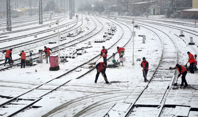Công nhân dọn tuyết trên đường ray bên ngoài một nhà ga xe lửa ở Nam Xương, tỉnh Giang Tây - Ảnh: Reuters
