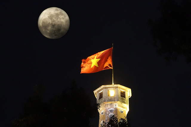   Trăng treo trên cột cờ Hà Nội lúc 20h. Siêu trăng là hiện tượng trăng ở vị trí rất gần trái đất so với cả quỹ đạo, vào đúng thời điểm trăng tròn.  