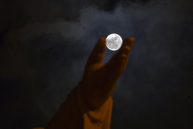   Siêu trăng nhìn qua bàn tay một bức tượng lớn. Độ sáng của siêu trăng cũng hơn bình thường khoảng 30%.  