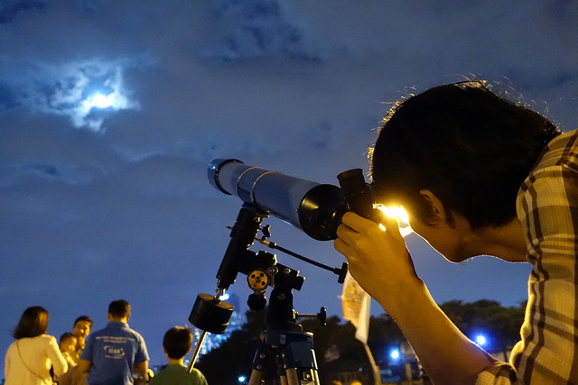   Nam thanh niên say sưa quan sát siêu trăng qua kính thiên văn.  