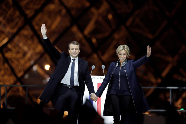 Ông Macron không ngần ngại công khai chuyện tình vốn được cho là “đũa lệch” của mình và luôn tự hào giới thiệu bà Brigitte với những người ủng hộ. Ngay cả những người con riêng của bà Brigitte cũng ủng hộ mối quan hệ của mẹ với cha dượng Macron. Người con gái thứ hai của bà Brigitte là Tiphaine Auziere cũng từng làm việc trong chiến dịch tranh cử của ông Macron và ca ngợi ông là một “người đàn ông thông minh” và “có tính cách đặc biệt”. Trong ảnh: Ông Macron nắm tay vợ trên sân khấu ăn mừng chiến thắng bầu cử hôm 7/5 bên ngoài bảo tàng Louvre tại Paris.