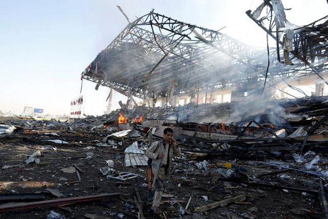 Tay súng Houthi bước qua đống đổ nát sau cuộc không kích nhằm vào một quảng trường ở Sanaa, Yemen hồi tháng 11.