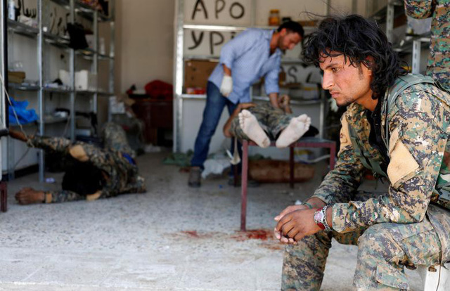 Một chiến binh thuộc Lực lượng Dân chủ Syria ngồi chờ bên ngoài một bệnh viện dã chiến khi các đồng đội bị thương đang được điều trị. Các chiến binh này bị trúng đạn của một tay súng bắn tỉa thuộc tổ chức Nhà nước Hồi giáo tự xưng (IS) ở Raqqa, Syria.