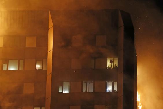 Một người bị mắc kẹt trong tòa nhà vẫy tay ra hiệu cho lực lượng cứu hỏa (Ảnh: Dailymail)