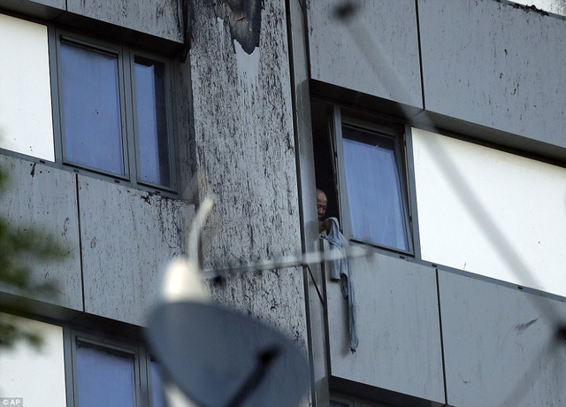 Một cư dân trong tòa tháp dùng áo để ra dấu hiệu cho lực lượng cứu hỏa (Ảnh: AP)