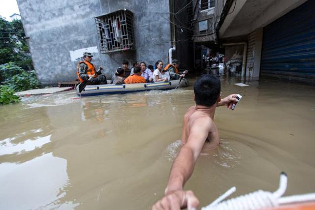 Theo chính quyền tỉnh Hồ Nam, người dân buộc phải đi sơ tán. Lũ lụt đã tàn phá mùa màng, phá hoại cơ sở vật chất. gây ra thiệt hại về kinh tế ước tính khoảng 1,22 tỷ USD. Trong ảnh: Đội cứu hộ dùng thuyền giải cứu người bị mắc kẹt trong trận lũ. (Ảnh: Reuters)