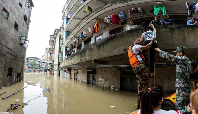   Ngày 3/7, những cơn mưa lớn đã gây ra lũ lụt nhấn chìm các thành phố miền Trung và miền Nam Trung Quốc như Hồ Nam, Hồ Bắc, An Huy, Tứ Xuyên và Quý Châu. Chính quyền xác nhận đã có 33 người chết và 15 người bị mất tích. Trong ảnh: Đội cứu hộ giúp sơ tán dân cư khỏi một khu vực đã ngập lụt hoàn toàn. (Ảnh: Reuters)  