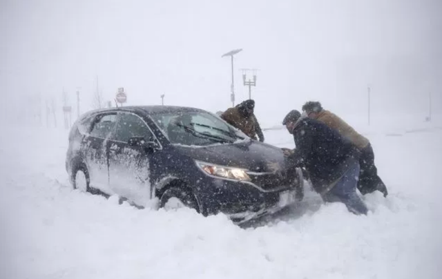 Theo CBS, ít nhất 22 người đã thiệt mạng tại các bang ở Mỹ khi “bom bão tuyết” lịch sử đổ bộ vào khu vực đông bắc nước này trong những ngày vừa qua. Trong ảnh: Những người đàn ông tìm cách giúp một người đi xe máy bị mắc kẹt trong tuyết ở bang New Jersey hôm 4/1. (Ảnh: AP)