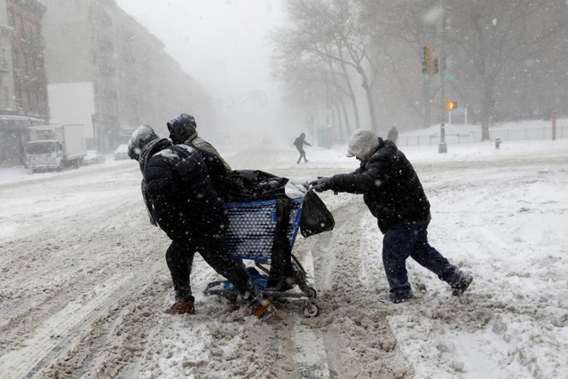   Nhiệt độ tại nhiều bang giảm xuống 20-30 độ so với mức bình thường, thậm chí tại những nơi gió thổi mạnh, nhiệt độ có thể xuống tới -23 độ C. Trong ảnh: Những người dân vất vả kéo xe chở đồ qua còn đường phủ đầy tuyết ở New York (Ảnh: Reuters)  