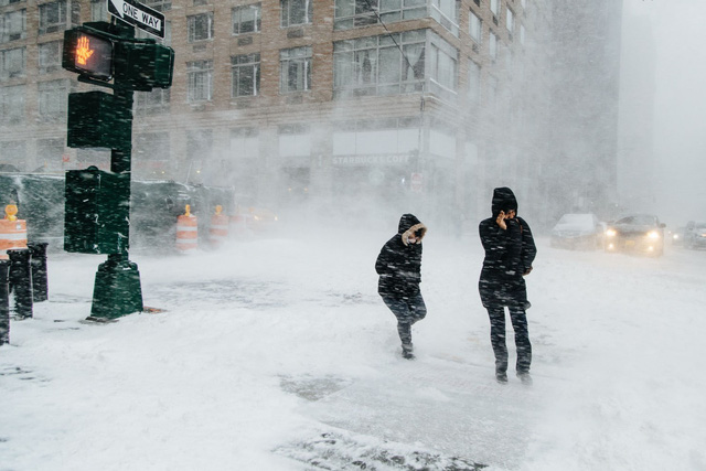 “Bom bão tuyết” khiến nhiều khu vực ở thành phố New York chìm trong khối tuyết dày, trong khi tại New England, ước tính cứ một giờ tuyết sẽ dày thêm 8 cm. Trong ảnh: Người đi bộ “chống chọi” với gió tuyết để qua đường ở New York. (Ảnh: EPA)