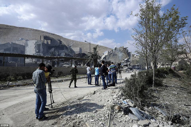   Các phóng viên ghi hình Trung tâm Barzah sau vụ không kích rạng sáng ngày 14/4. (Ảnh: EPA)  
