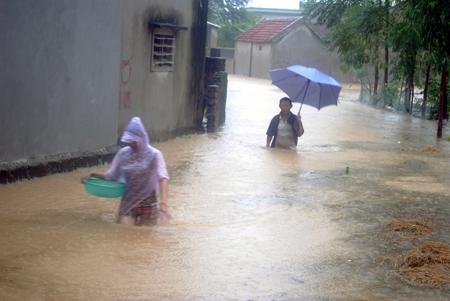 Lội nước lũ ra khỏi làng tại xã Khánh Thành.