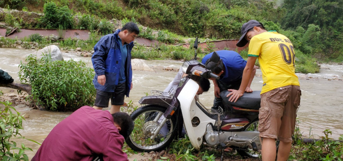 Các thầy giáo sửa xe sau khi qua suối để tiếp tục hành trình đón học sinh. Ảnh: Duy Nguyễn.