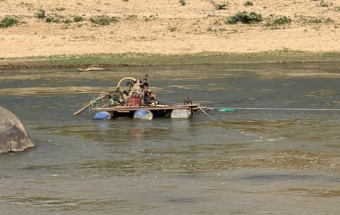 Hai đối tượng dùng máy nổ để hút cát dưới sông. Ảnh: Quang Yên.