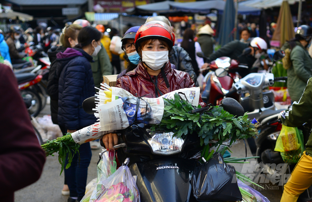 Một phụ nữ chất đầy hoa, trái cây, thực phẩm rời khỏi chợ Tết để về nhà.