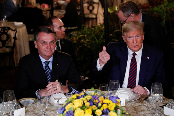 Ông Bolsonaro và ông Trump ngồi cạnh nhau tại bàn tiệc chiêu đãi ở khu nghỉ dưỡng Mar-a-Lago, bang Florida. Ảnh: Reuters.