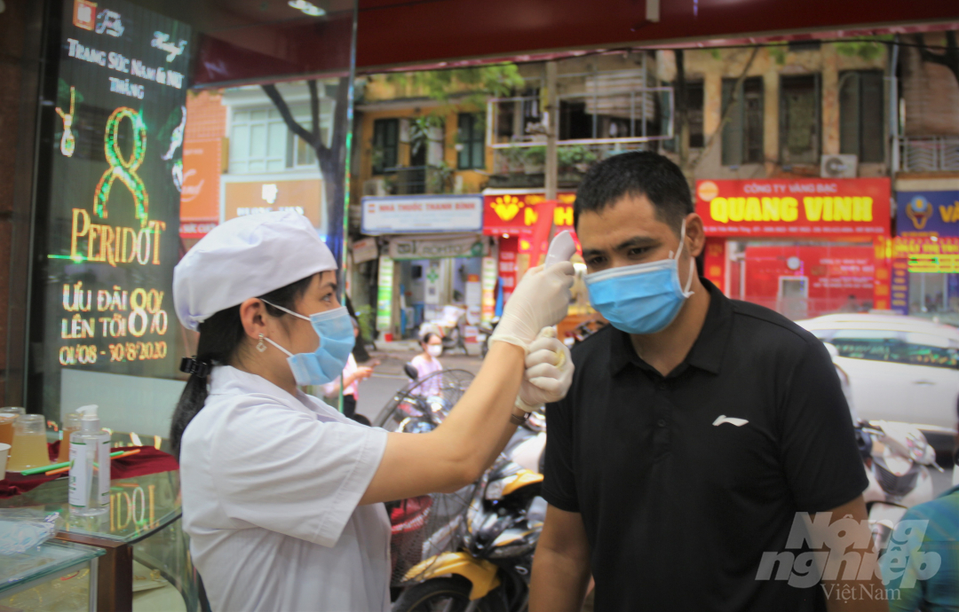 Tại một cửa hàng trên phố Trần Nhân Tông, khách hàng tới giao dịch sẽ được phát khẩu trang, đo thân nhiệt và rửa tay sát khuẩn để phòng tránh dịch bệnh Covid-19. Ảnh: Phạm Hiếu.