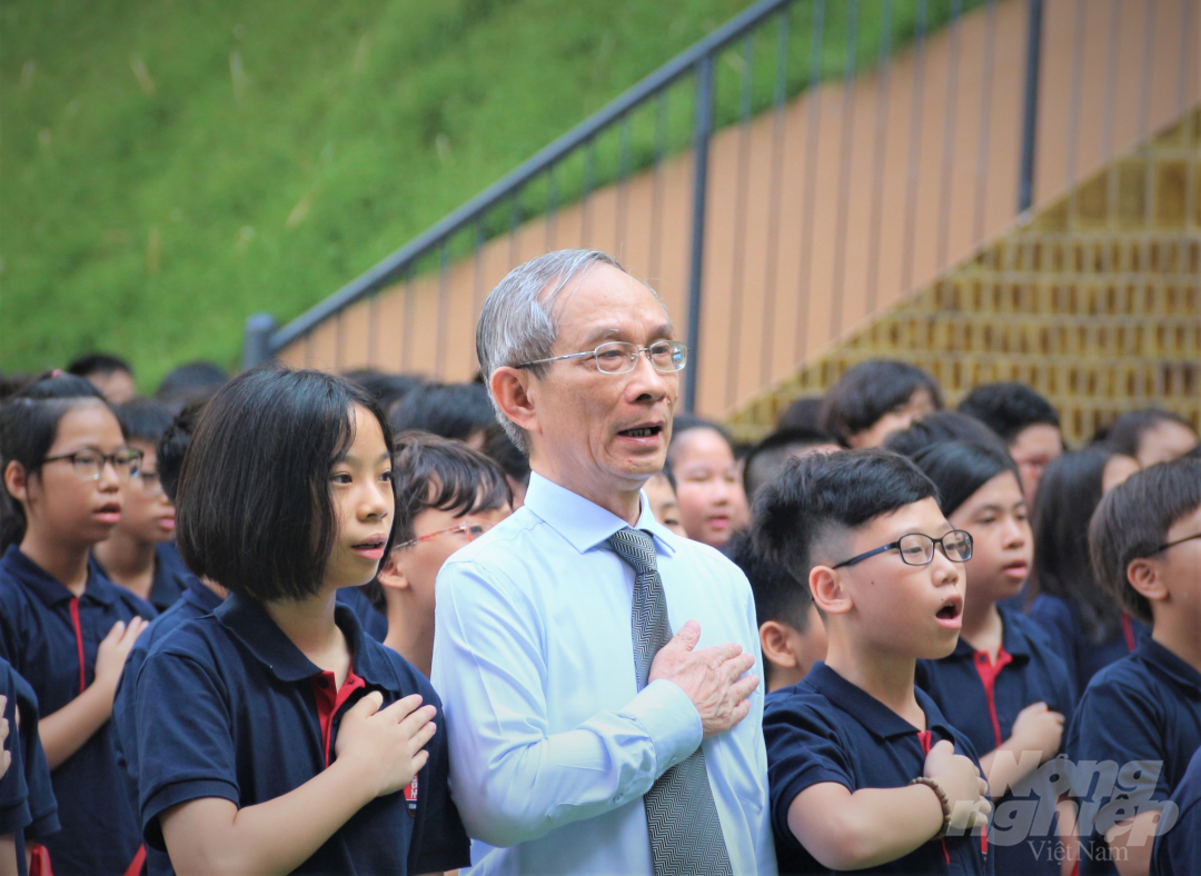 Hiệu trưởng nhà trường, thầy Nguyễn Xuân Khang cùng các em học sinh cất tiếng hát Quốc ca tại lễ khai giảng đặc biệt. Ảnh: Phạm Hiếu.