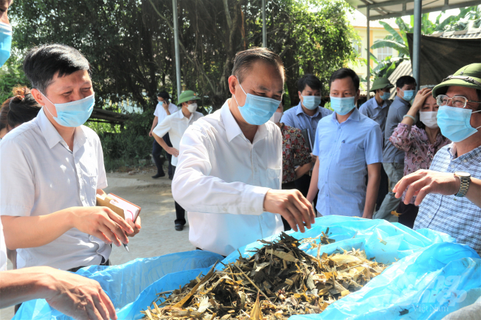 Thứ trưởng Phùng Đức Tiến (giữa) kiểm tra thức ăn chăn nuôi của người nông dân. Ảnh: Phạm Hiếu.