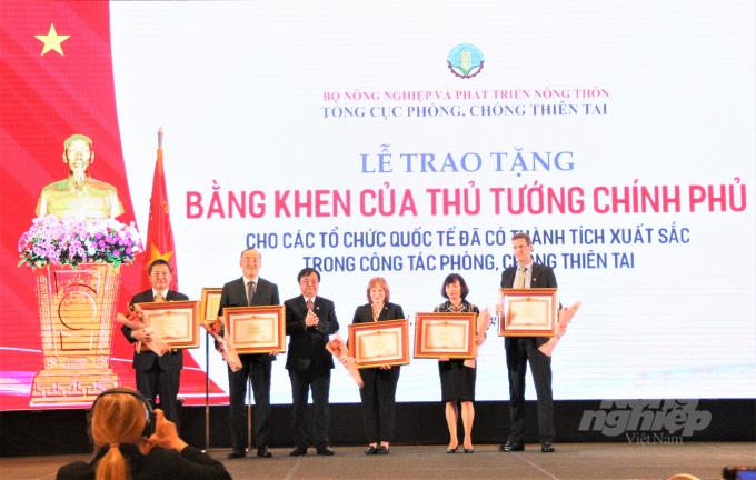 Bộ trưởng Bộ NN-PTNT Lê Minh Hoan (giữa) trao bằng khen của Thủ tướng Chính phủ cho các tổ chức quốc tế đã có thành tích xuất sắc trong phòng, chống thiên tai. Ảnh: Phạm Hiếu.