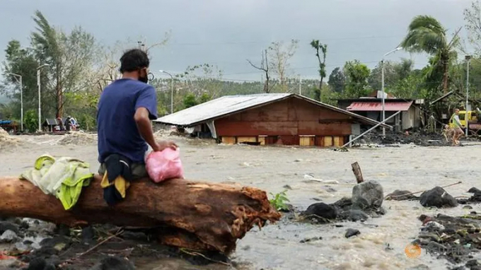 Một người dân bị kẹt giữa dòng lũ dữ ở Virac. Ảnh: Reuters.