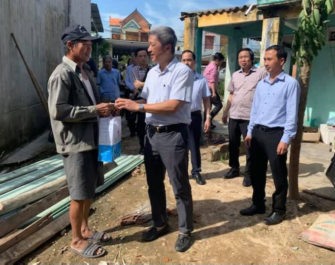 Thứ trưởng Nguyễn Trường Sơn thăm và tặng quà gia đình người dân xã Tam Phú có nhà bị tốc mái trong bão số 9. Ảnh: BYT.