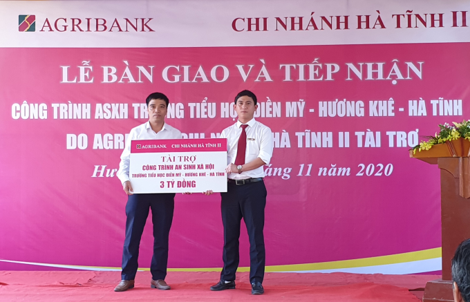 Ông Võ Văn Nhất (bên phải), Giám đốc Agribank Hà Tĩnh II trao biển biểu trưng 3 tỷ đồng tài trợ xây dựng Trường tiểu học Điền Mỹ. Ảnh: Thanh Nga.