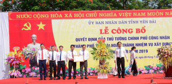 Ông Nguyễn Văn Khánh - Phó Chủ tịch tỉnh Yên Bái trao chứng nhận và tặng hoa cho lãnh đạo TP. Yên Bái. Ảnh: Thái Sinh.