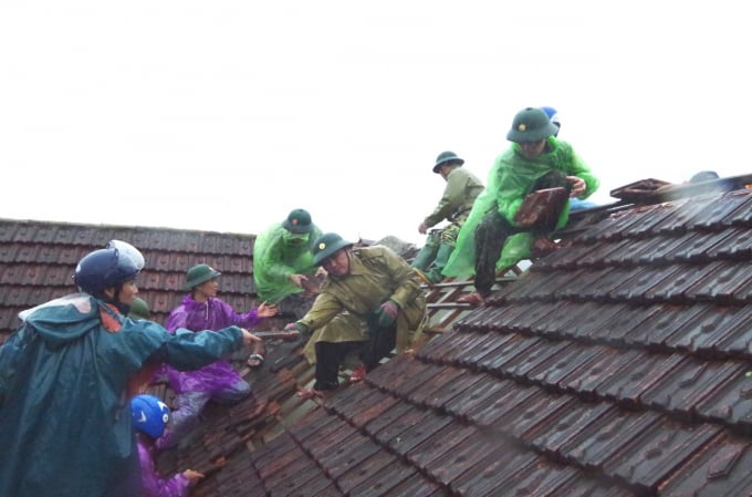 Lực lượng chức năng hỗ trợ lợp lại mái nhà cho người dân.