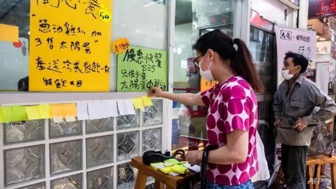 Một phụ nữ dán mảnh giấy ghi chú trống lên tường một nhà hàng ở Hong Kong hôm 3/7. Ảnh: AFP.