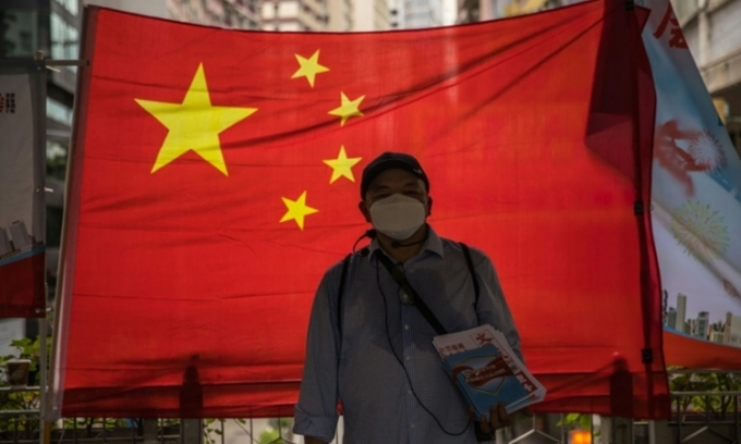 Một người ủng hộ Bắc Kinh phát báo trước cờ Trung Quốc tại Hong Kong ngày 1/7. Ảnh: AFP.