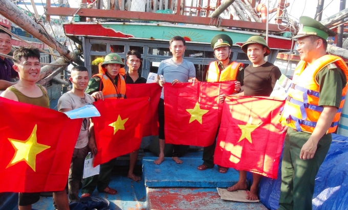 Bộ đội Biên phòng Quảng Bình tặng cờ Tổ quốc cho ngư dân tàu cá xa bờ trước lúc xuất bến. Ảnh: Công Điền.