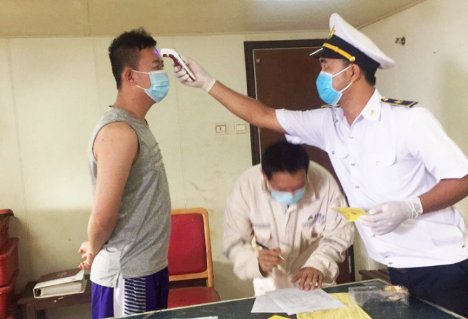 Cán bộ trung tâm phòng chống bệnh tật tỉnh Quảng Bình đo thân nhiệt, kiểm tra sức khỏe các thủy thủ tàu Amoy Dream . Ảnh: H.P.