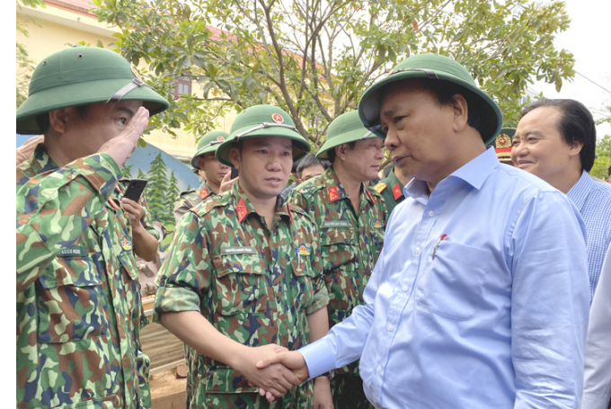 Thủ tướng Nguyễn Xuân Phúc động viên cán bộ, chiến sỹ giúp dân dọn vệ sinh, khắc phục hậu quả mưa lũ tại xã Hiền Ninh. Ảnh: T.Phùng