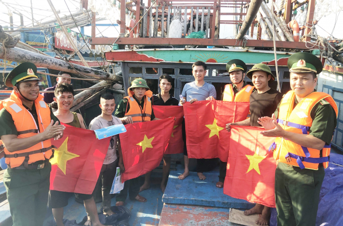 Bộ đội Biên phòng Quảng Bình tặng áo phao và cờ Tổ quốc cho ngư dân trước lúc tàu ra khơi. Ảnh: N.Tâm
