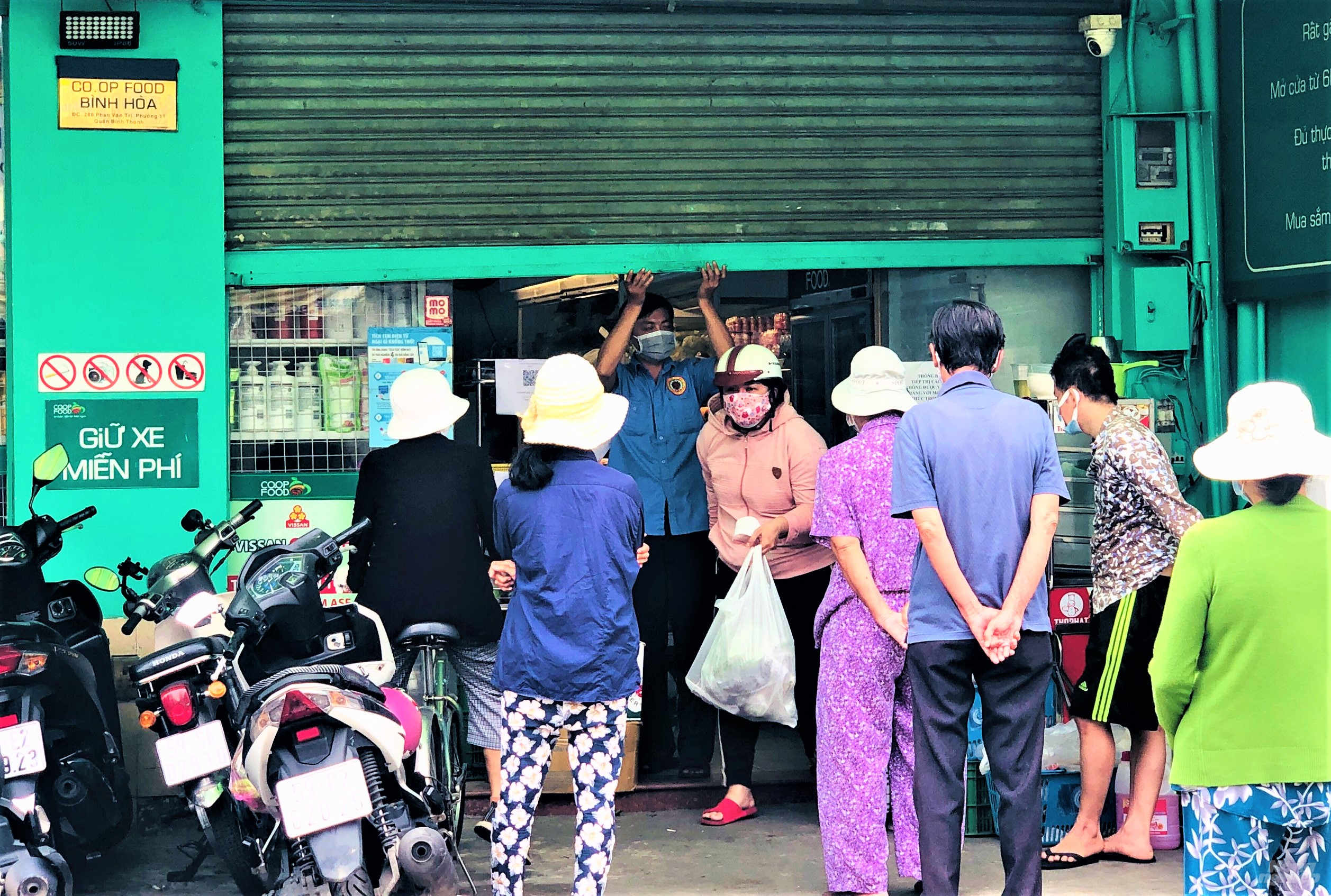 Tại Coop Food Bình Hòa chỉ cho vài người vào, sau đó kéo cửa xuống để tránh người vào quá đông, làm lây lan dịch bệnh. Nhiều người phải chờ rất lâu mới tới lượt vào. Ảnh: Minh Sáng.