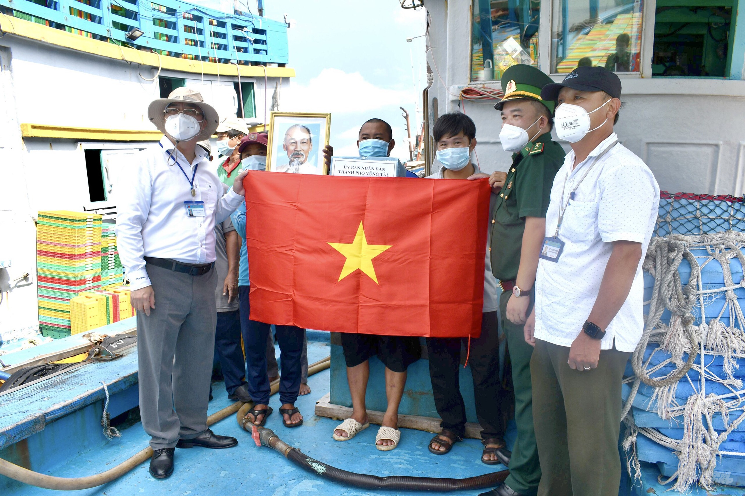 Ông Hoàng Vũ Thảnh, Chủ tịch UBND TP. Vũng Tàu (bên trái), tặng cờ Tổ quốc và ảnh Bác Hồ cho ngư dân tàu dịch vụ nghề cá. Ảnh: MV