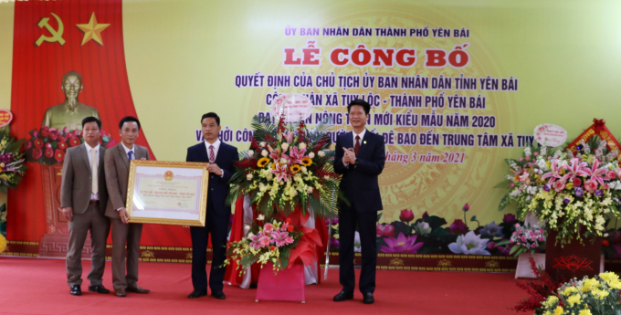 Ông Nguyễn Thế Phước- Phó Chủ tịch UBND tỉnh Yên Bái (phải) tặng hoa và chứng nhận xã đạt chuẩn NTM kiểu mẫu cho lãnh đạo xã Tuy Lộc. Ảnh: Thái Sinh.