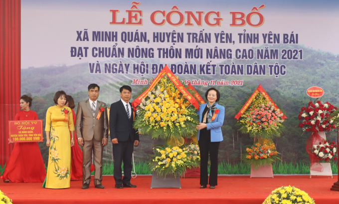 Bộ trưởng Phạm Thị Thanh Trà (phải) tặng lẵng hoa chúc mừng xã Minh Quán đạt chuẩn NTM nâng cao và Ngày hội Đại đoàn kết toàn dân tộc. Ảnh: Thái Sinh.
