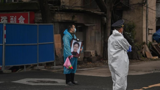 Một người đàn ông cầm theo di ảnh người thân ở bên ngoài nghĩa trang Biandanshan, Vũ Hán. Ảnh: Getty Images.